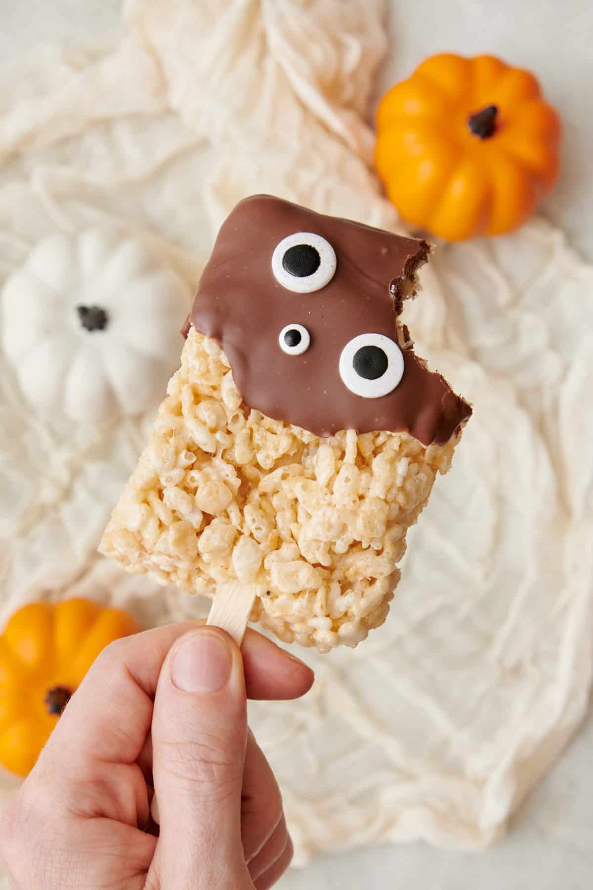 Chocolate dipped rice krispies with halloween decoration and a bite taken out.