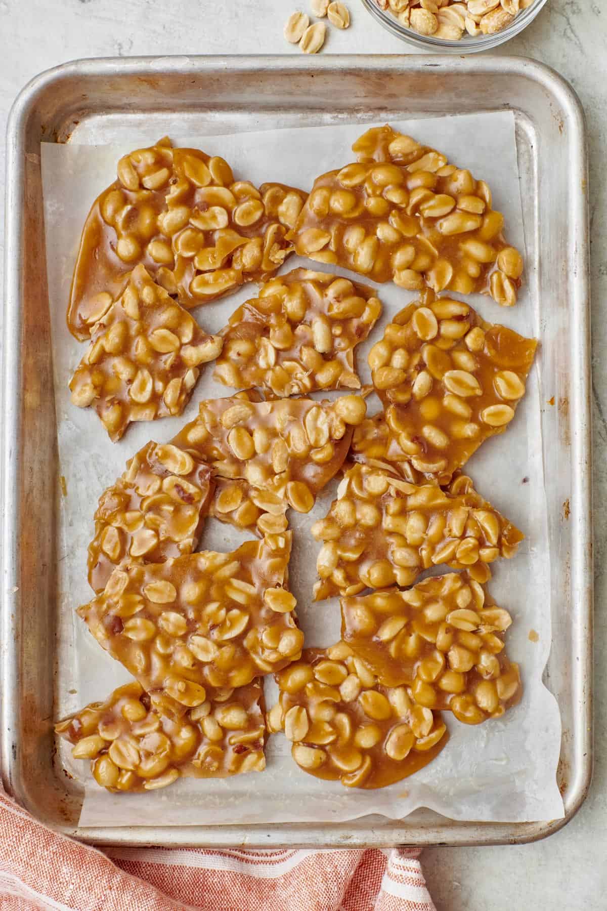 Homemade peanut brittle on a parchment lined sheet pan.