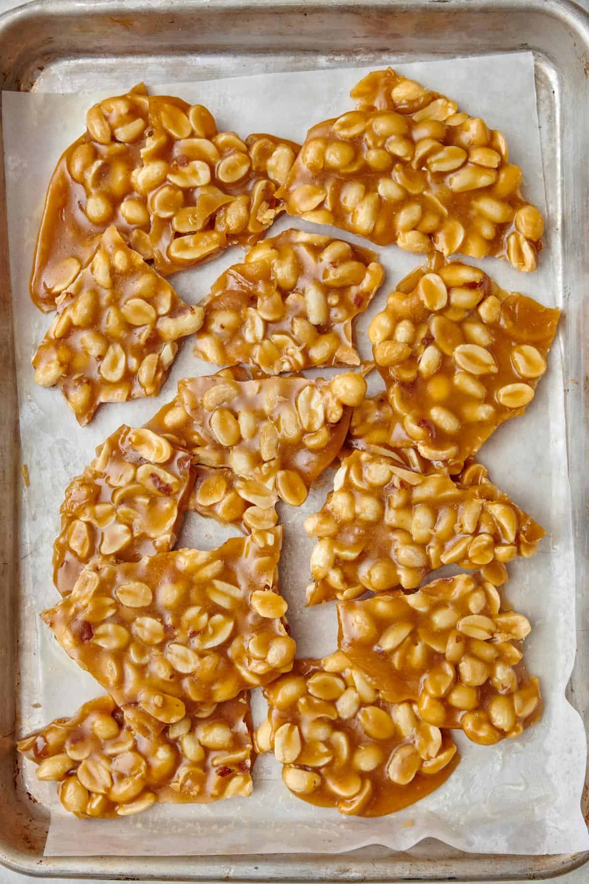 Peanut brittle broken into large pieces on a sheet pan.