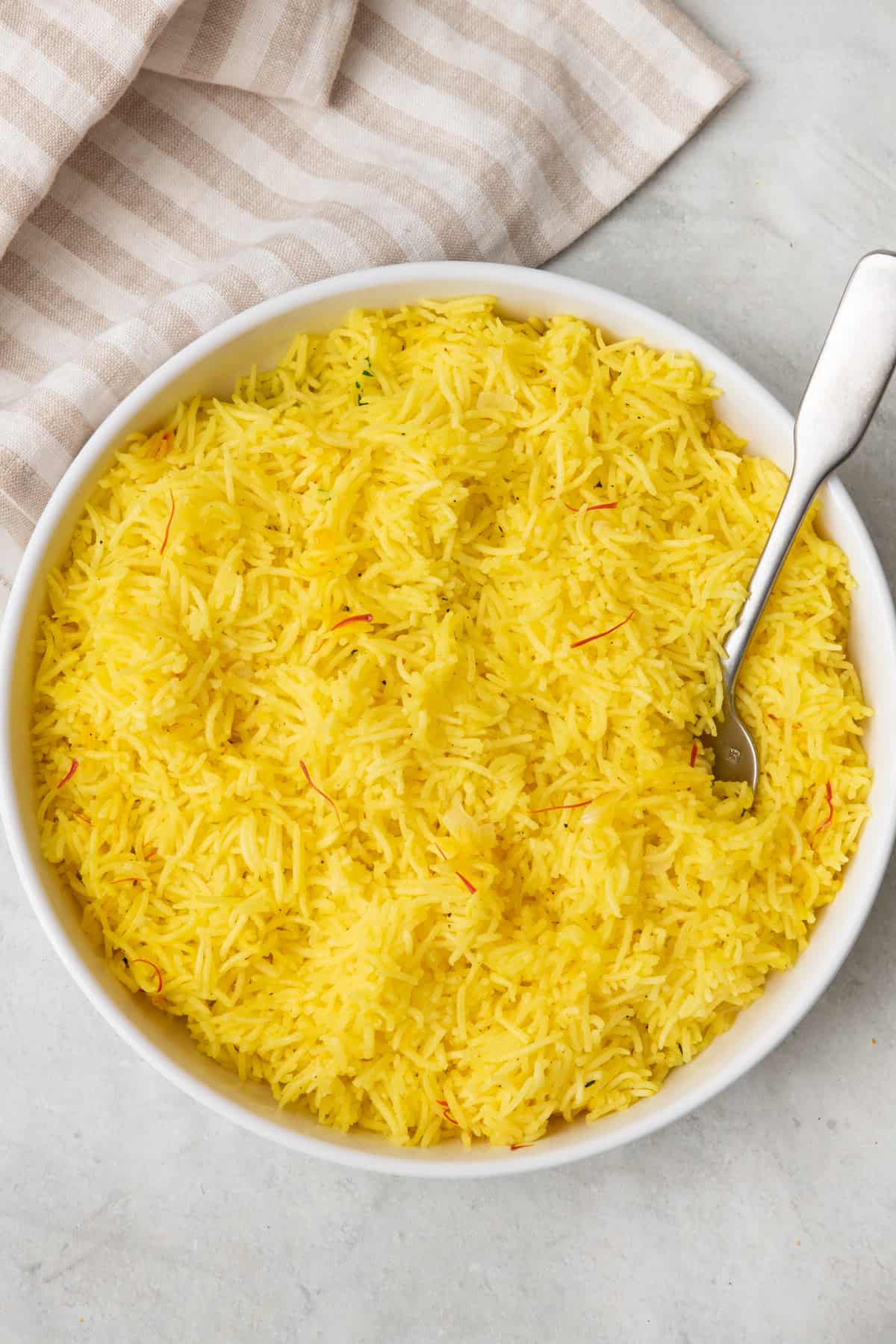 Bowl of saffron rice with a spoon dipped in.