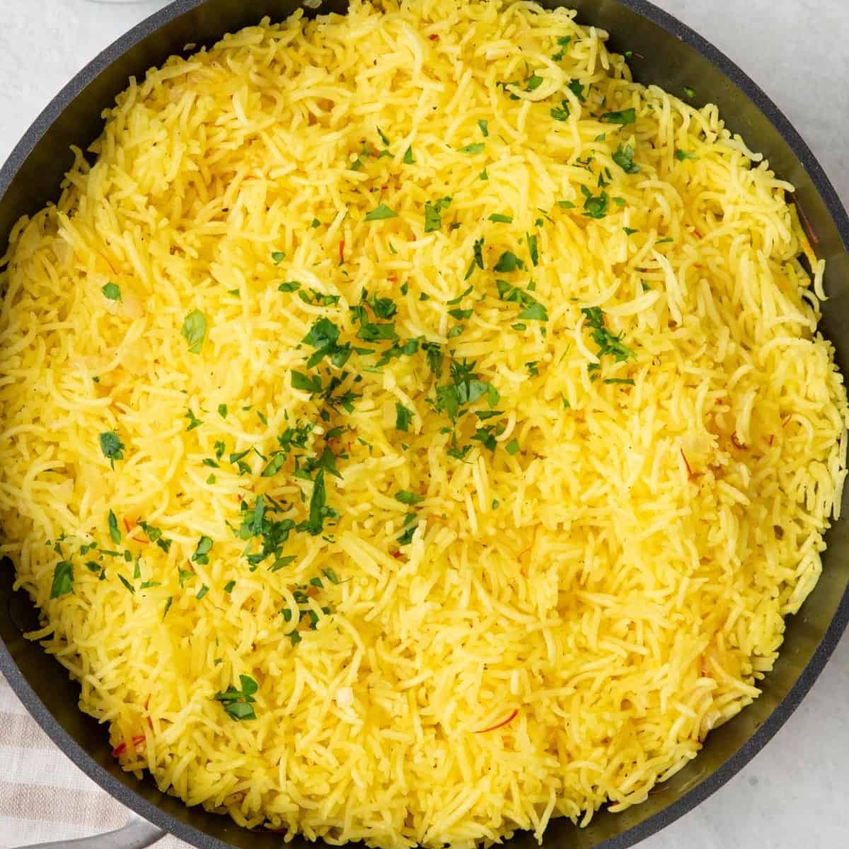 Square image of a pan of golden saffron rice.