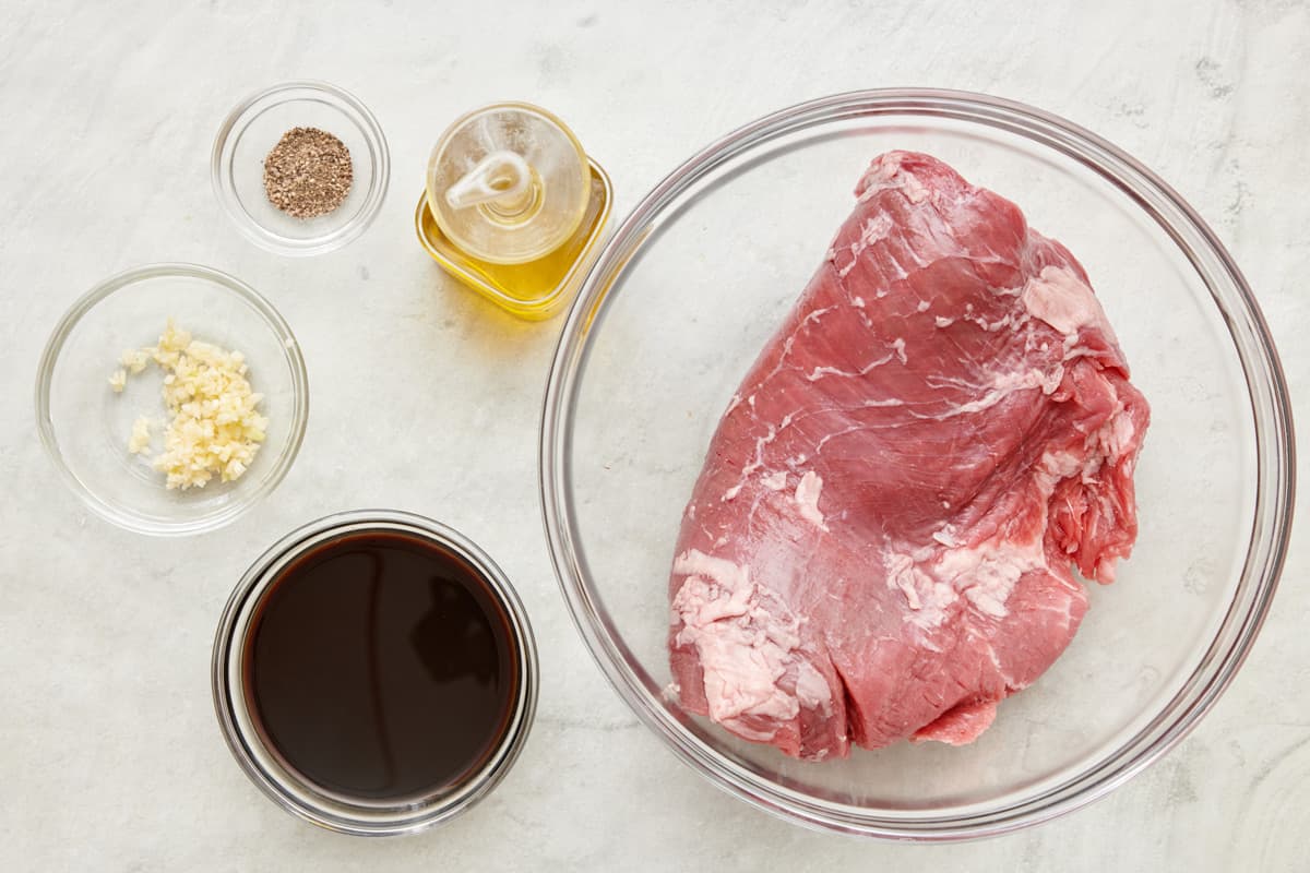 Ingredients for garlic Worcestershire steak marinade: minced garlic, black pepper, Worcestershire sauce, and a flank steak.
