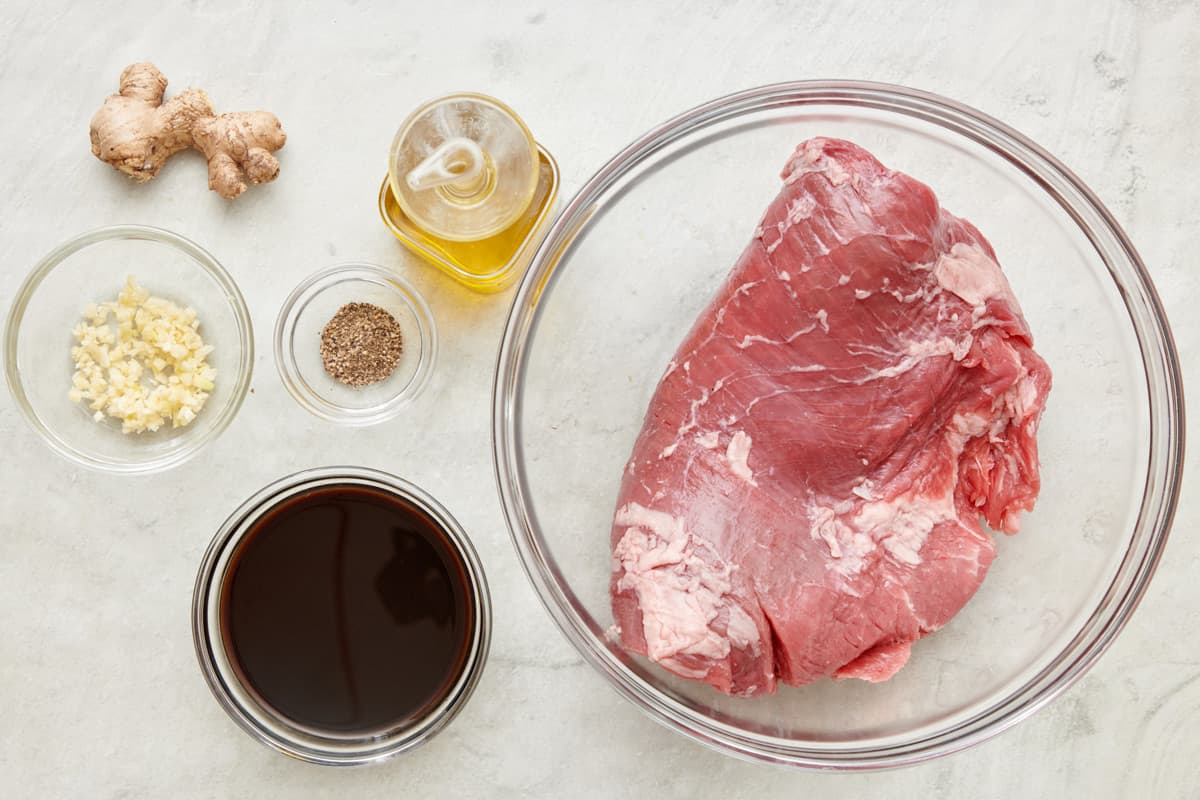 Ingredients for soy ginger marinade: thumb of ginger, minced garlic, black pepper, soy sauce, oil, and steak.