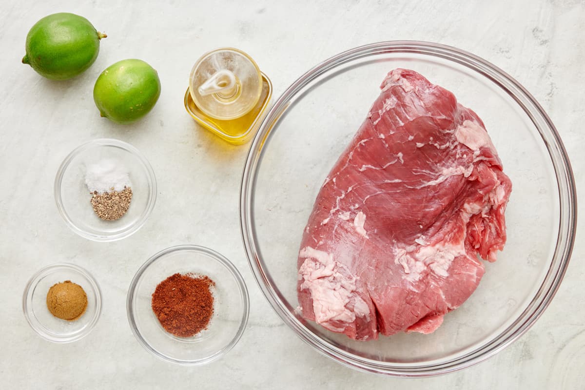 Ingredients for cumin lime marinade: limes, salt and pepper, cumin, chili powder, oil, and steak.