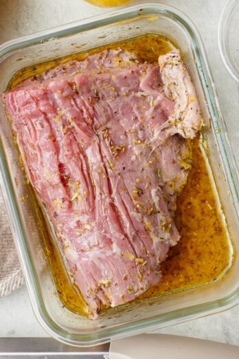 Square image of flank steak in marinade.