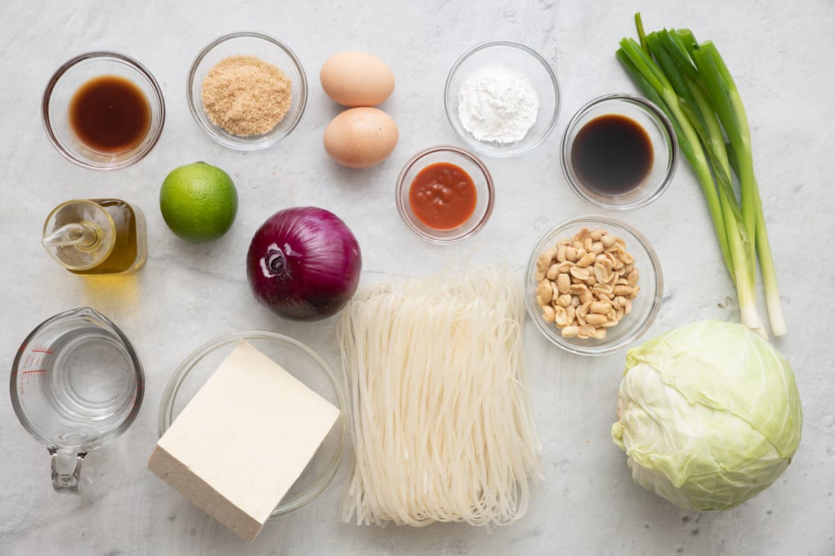 Ingredients for recipe: soy sauce, brown sugar, oil, lime, water, tofu block, eggs, sriracha, cornstarch, rice noodles, peanuts, fish sauce, peanuts, green onions, and cabbage.