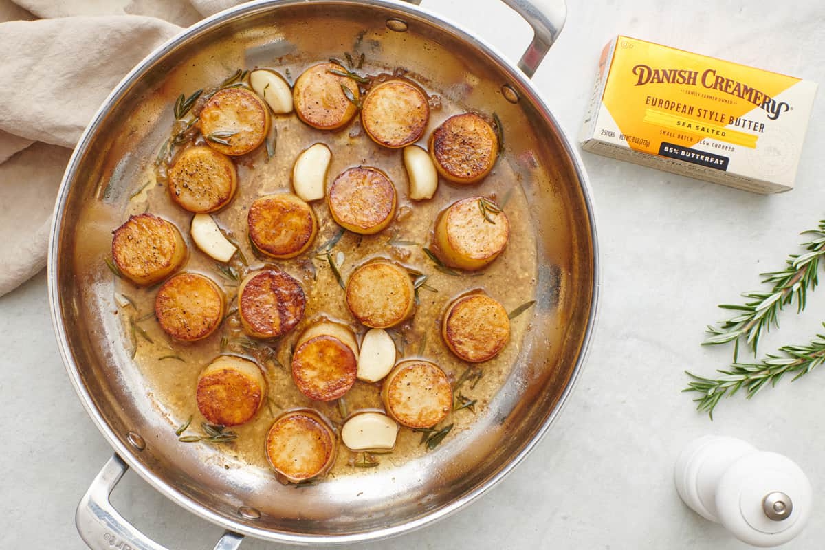 Fondant melting potatoes in a skillet made with Danish Creamery European Sea Salted Butter with a box of butter nearby.