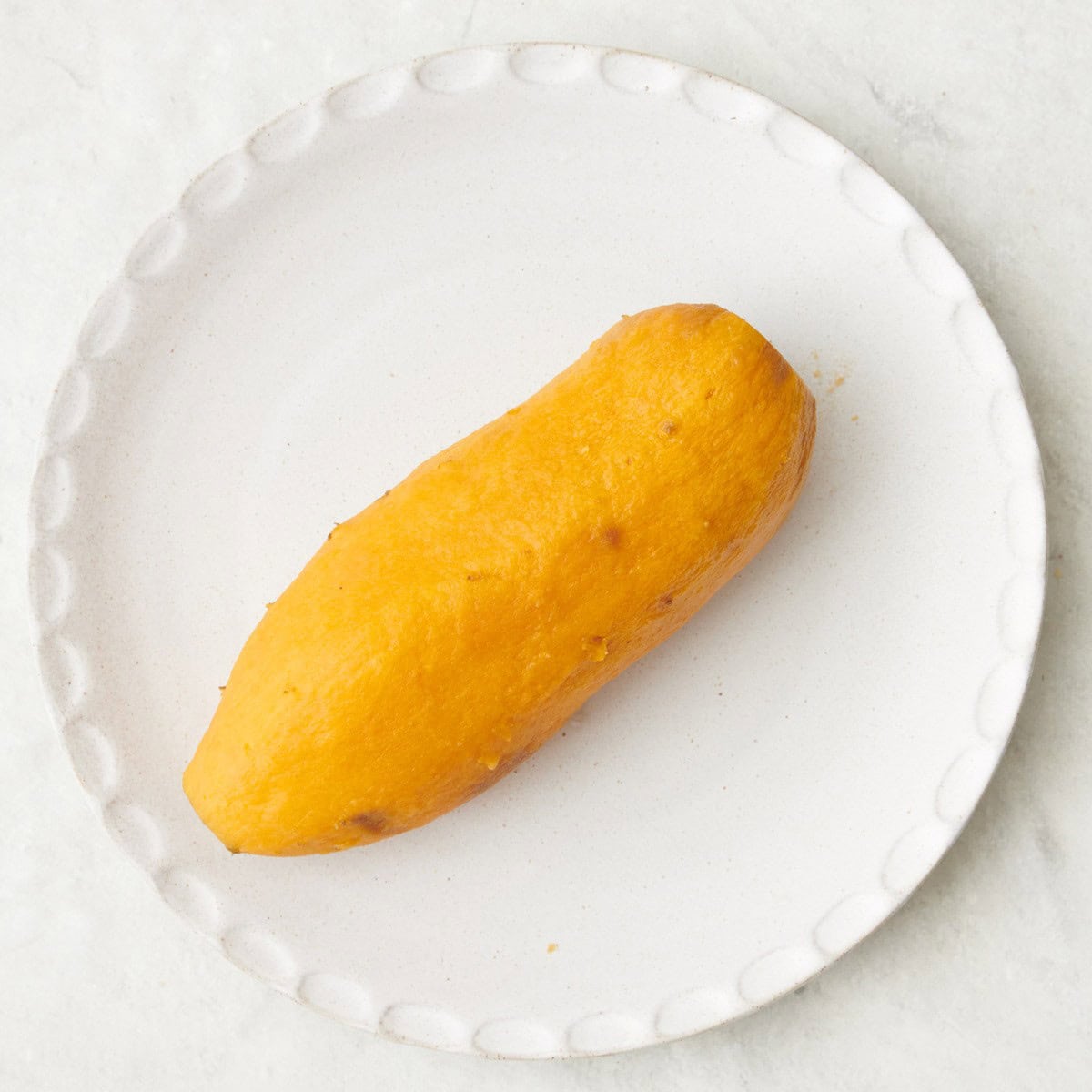 Sweet potato still on plate and peeling off the skin.