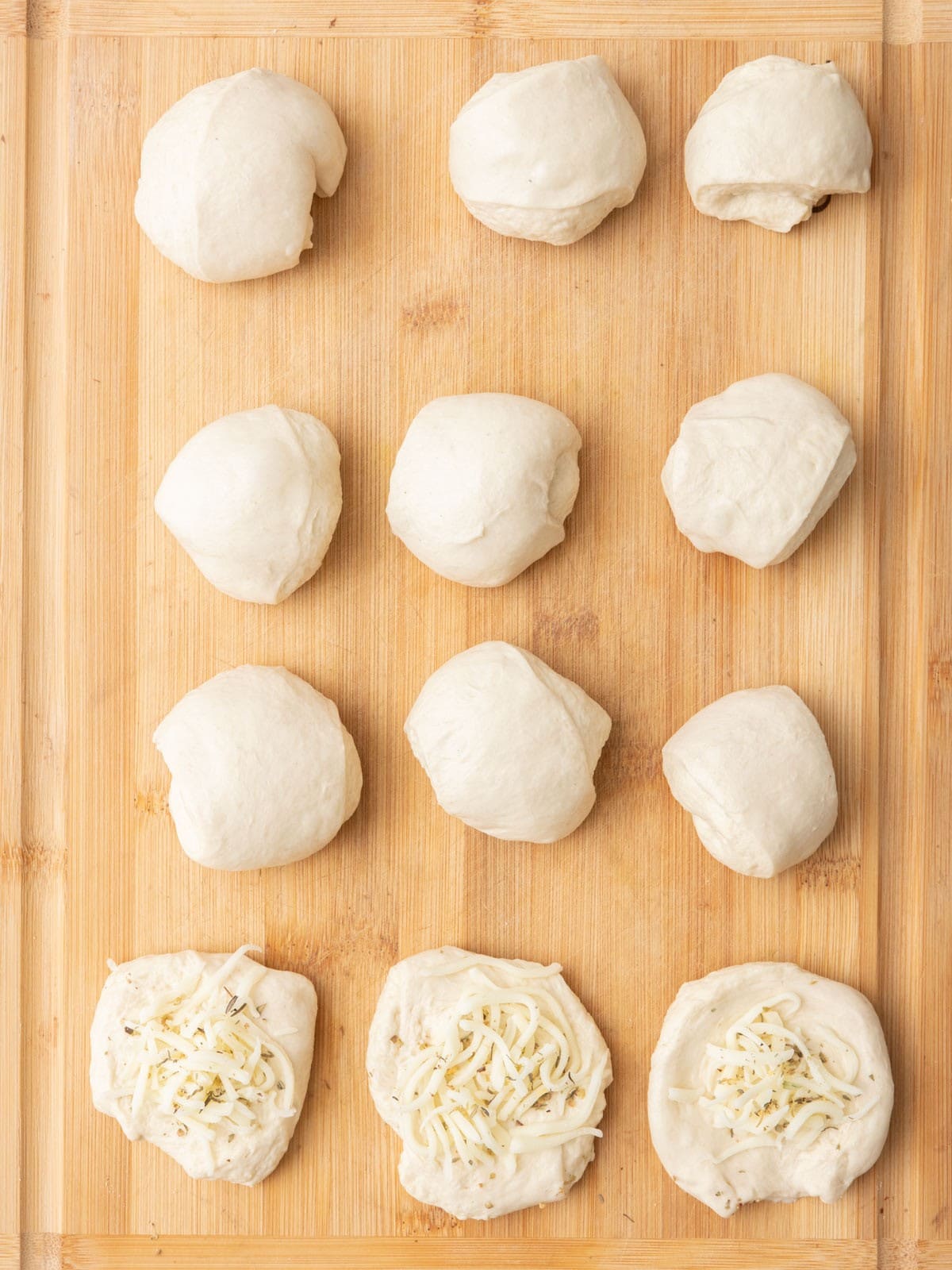 Few flat pizza rounds on cutting board filled with cheese and seasoning.
