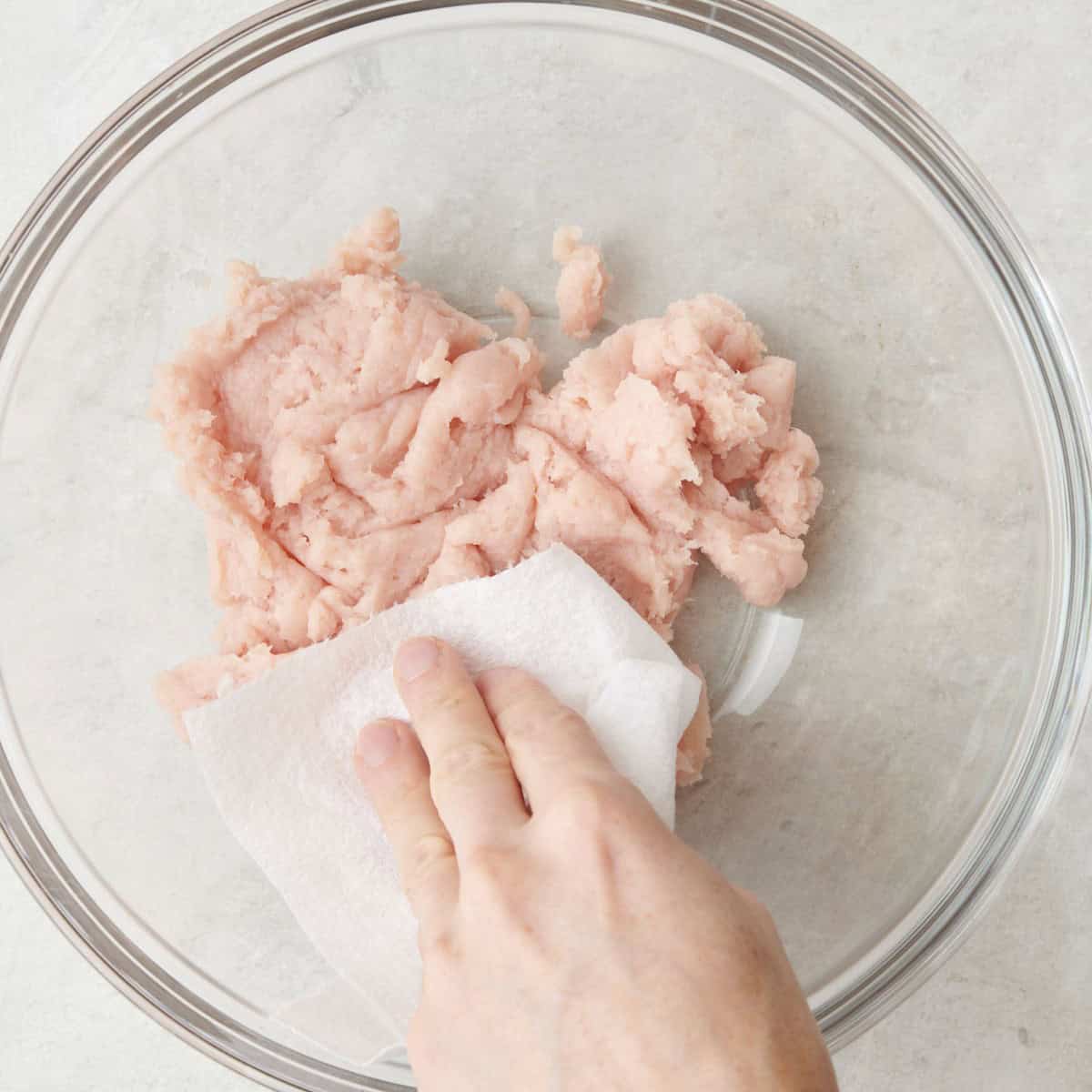 Ground chicken in large bowl with paper towel dabbing dry.