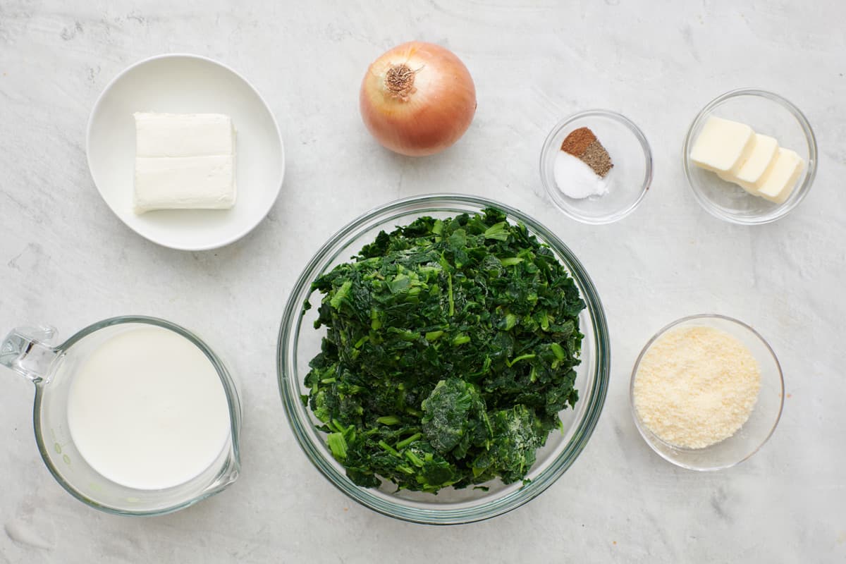 Ingredients for recipe in individual dishes: cream cheese, milk, onion, frozen spinach, seasoning, butter, and parmesan.