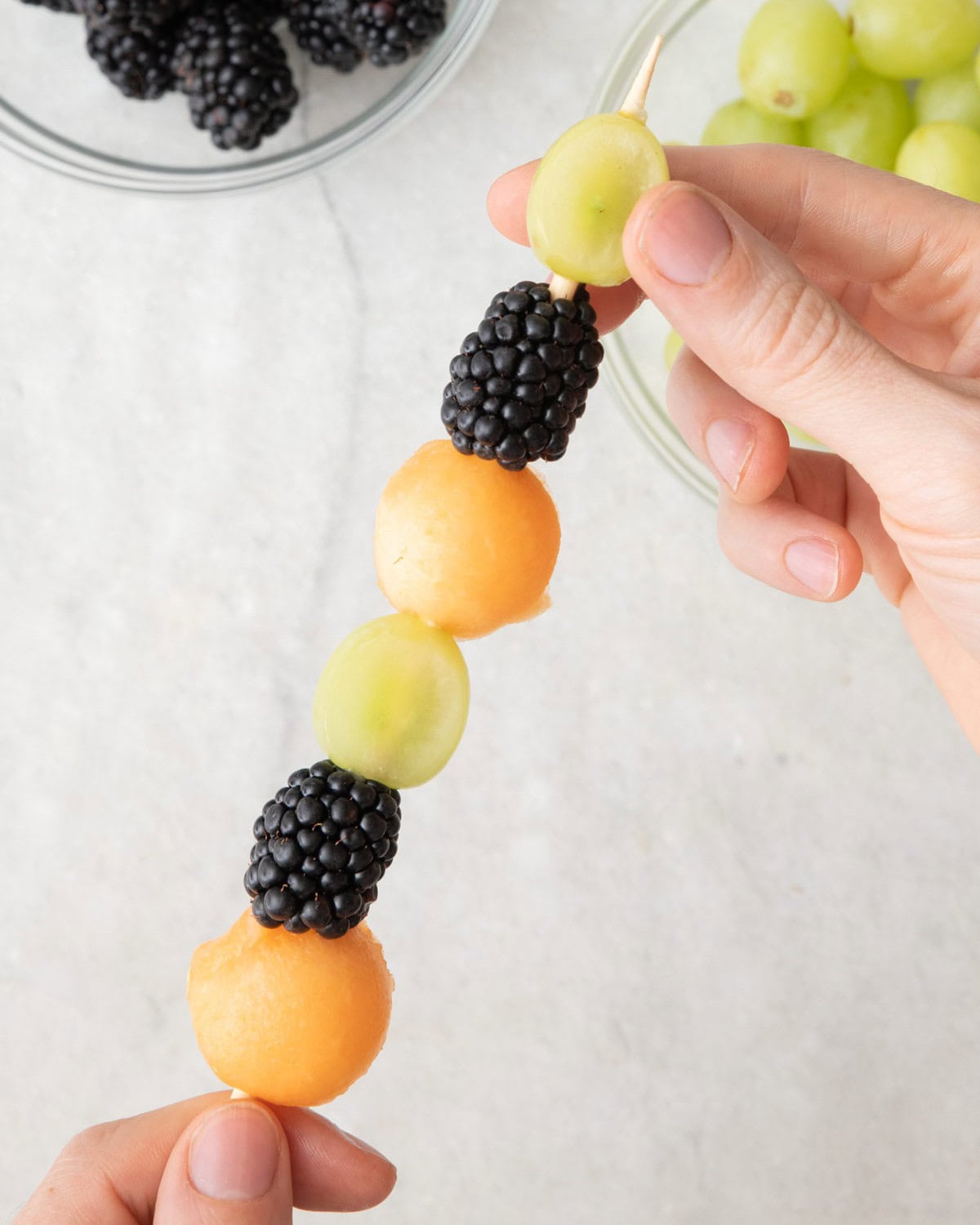 Threading fruit onto skewers.