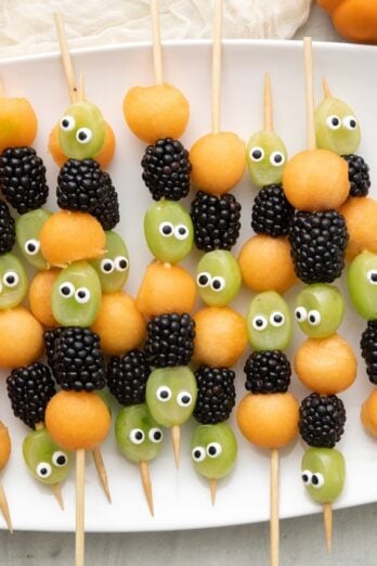 Halloween fruit kabobs on a tray with Halloween decor.