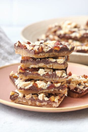Stack of homemade toffee on a plate with more nearby.