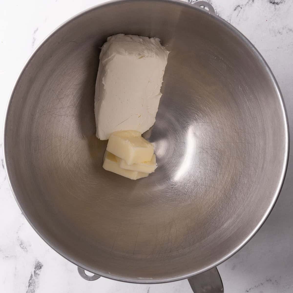 Cream cheese and butter in bowl of stand mixer before mixing.