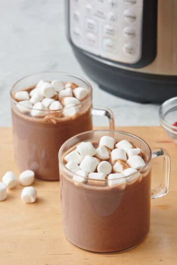 Instant pot hot chocolate served in two glass mugs and topped with mini marshmallows.