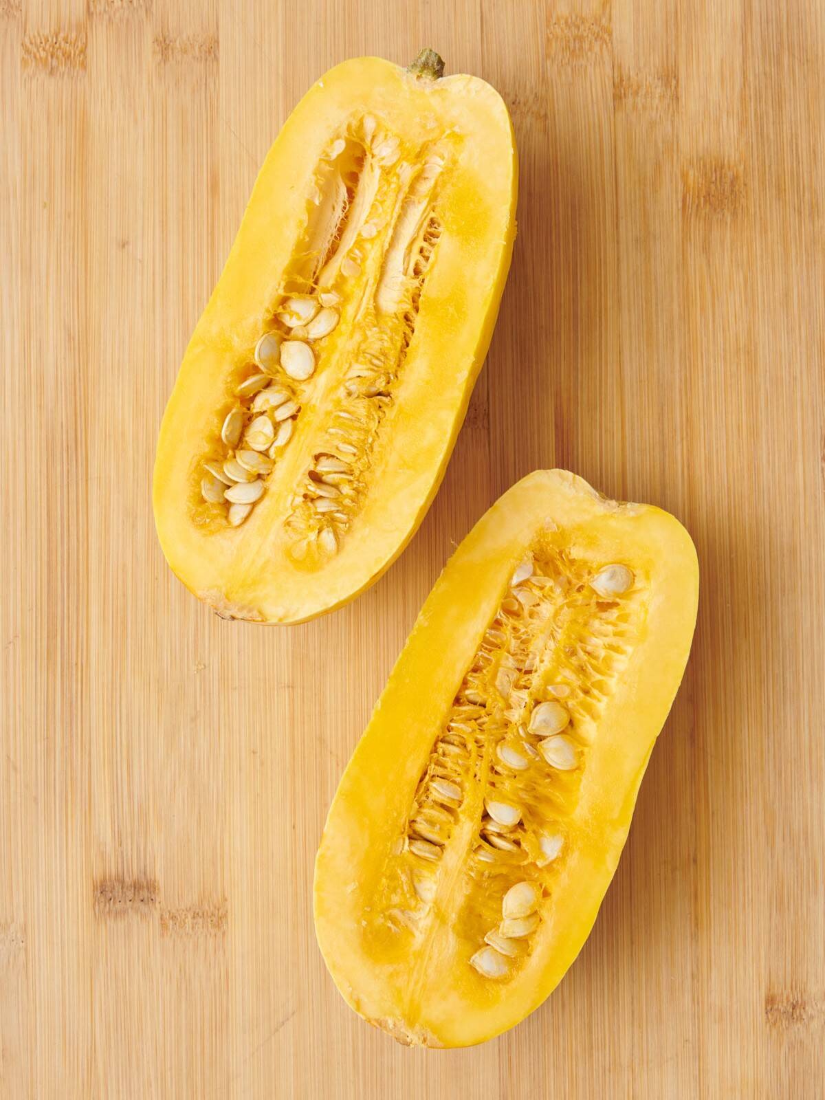 Squash cut in half lengthwise on cutting board.