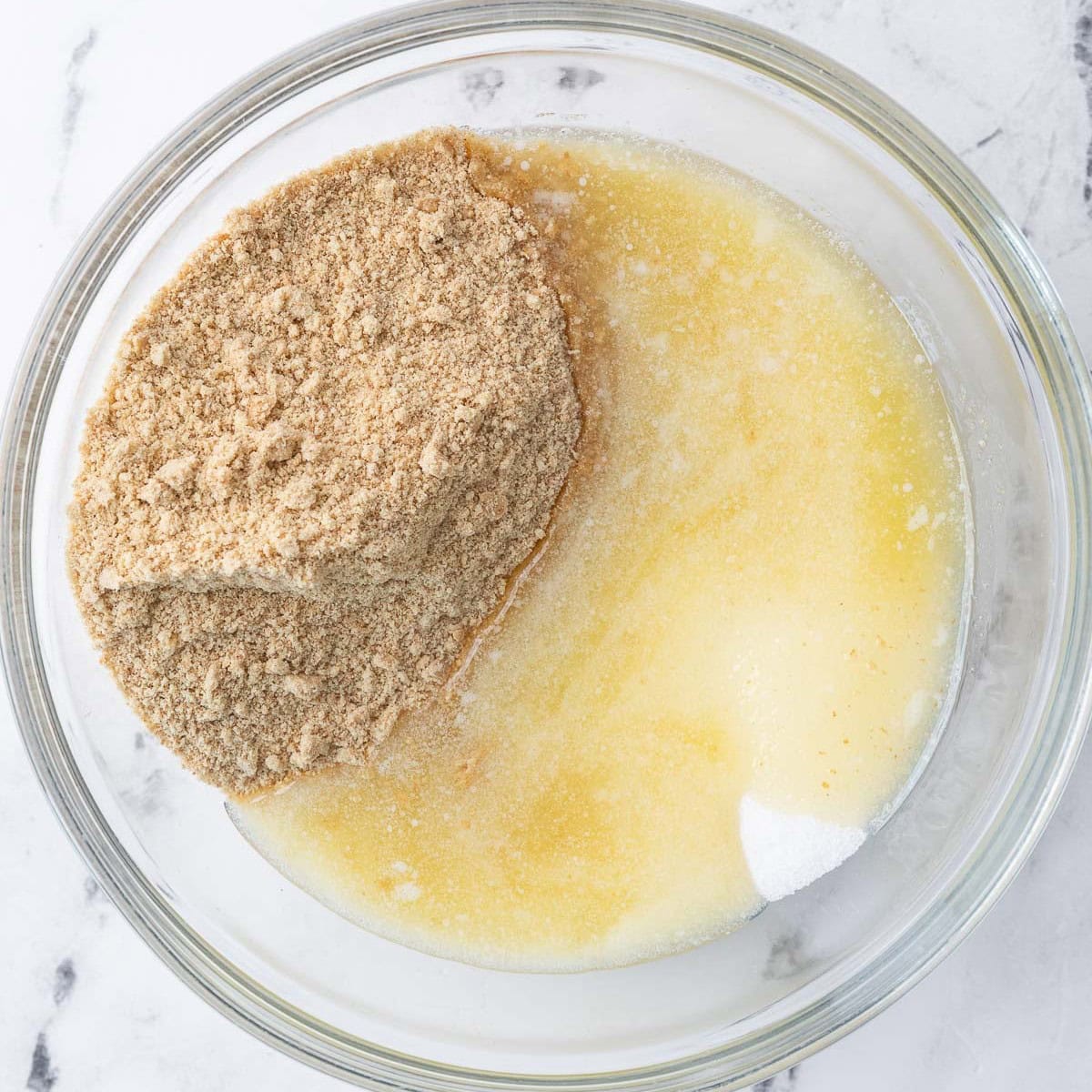 Graham cracker crumbs, sugar, and melted butter in a bowl before mixing.