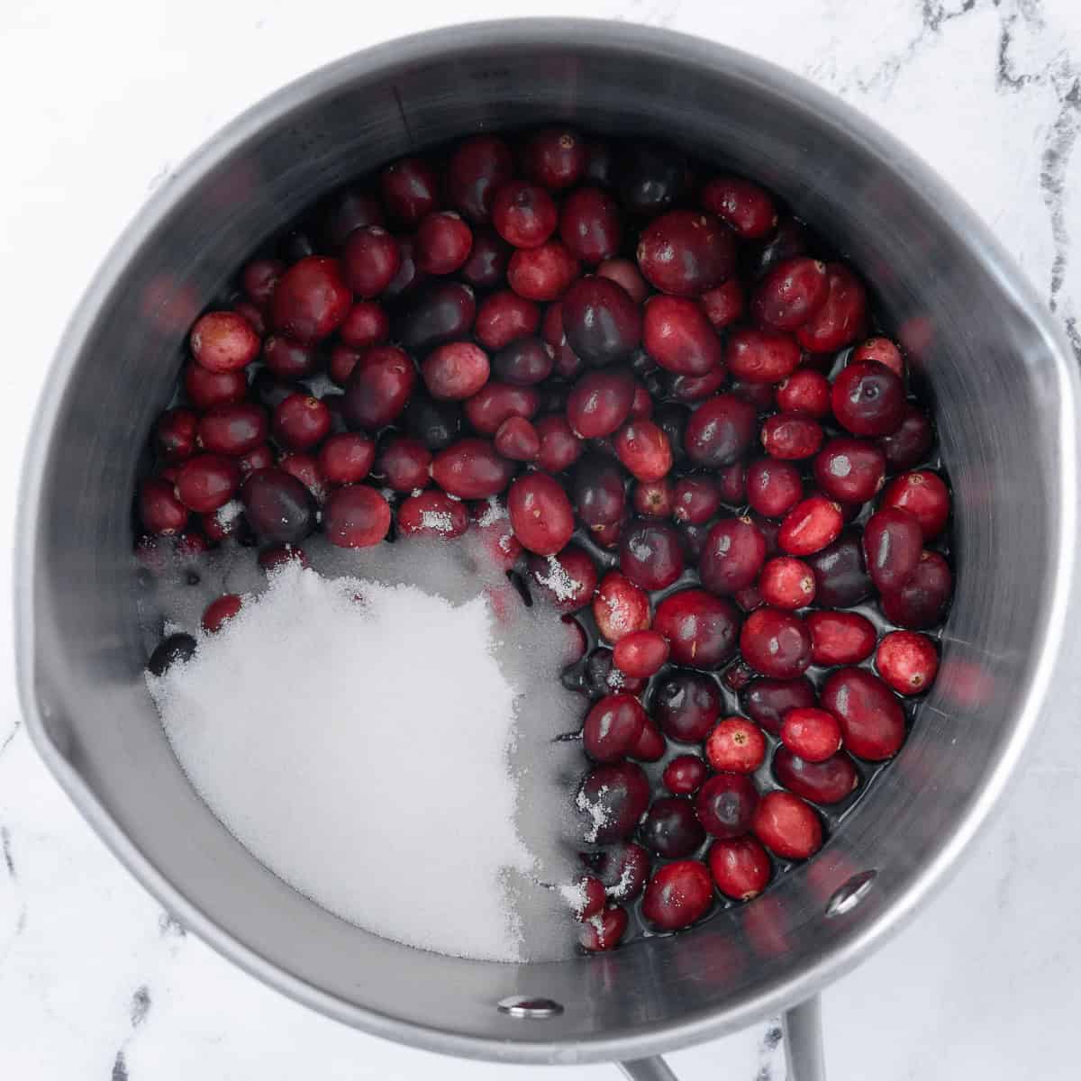 Cranberries, sugar and water in a saucepan before combined.