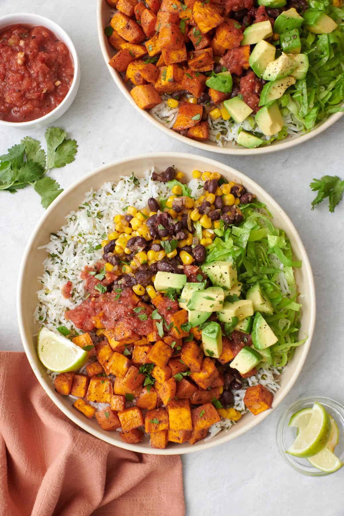 Two Vegetarian burrito bowls with cilantro lime rice, avocado, lettuce, and salsa.