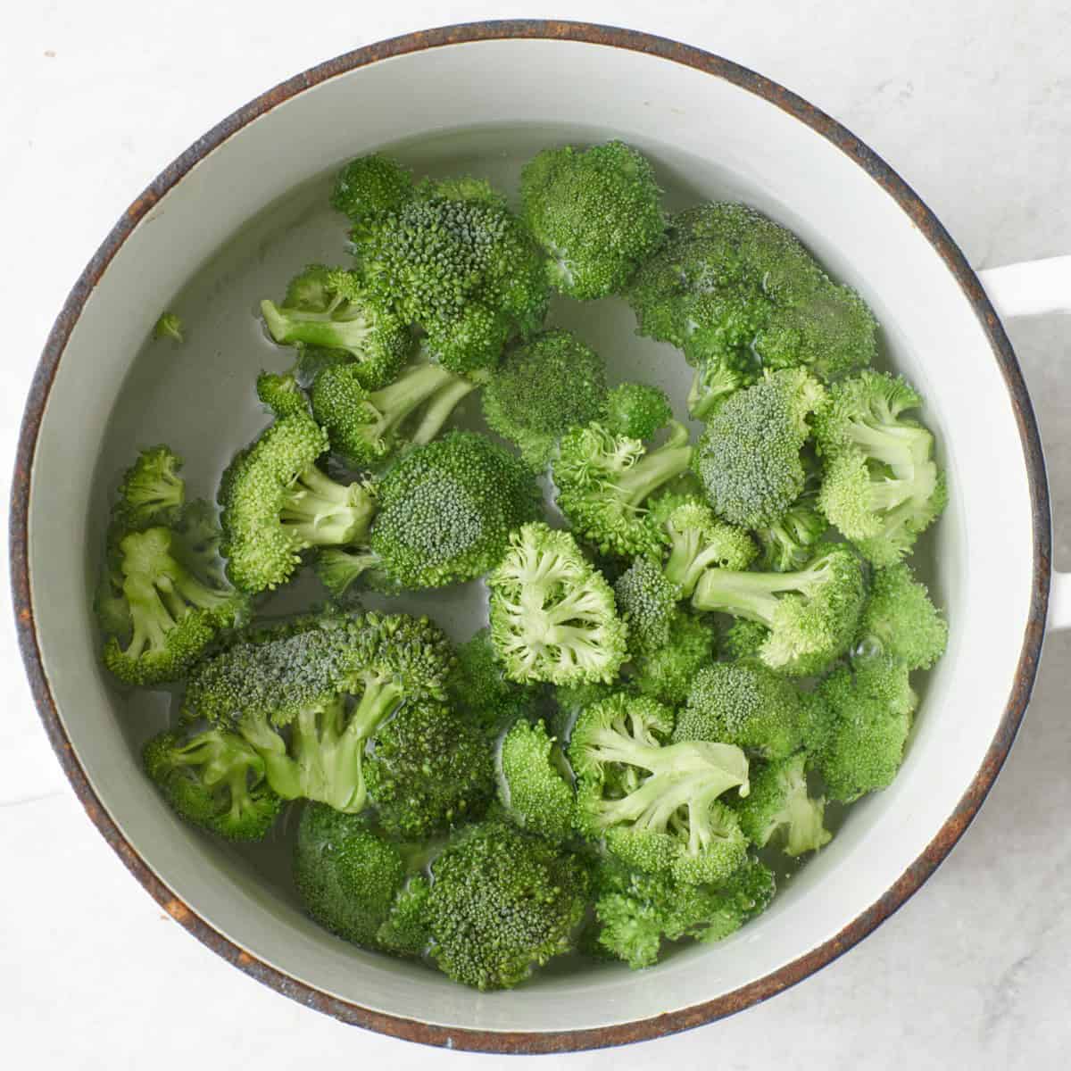 Broccoli florets in a pot of water.