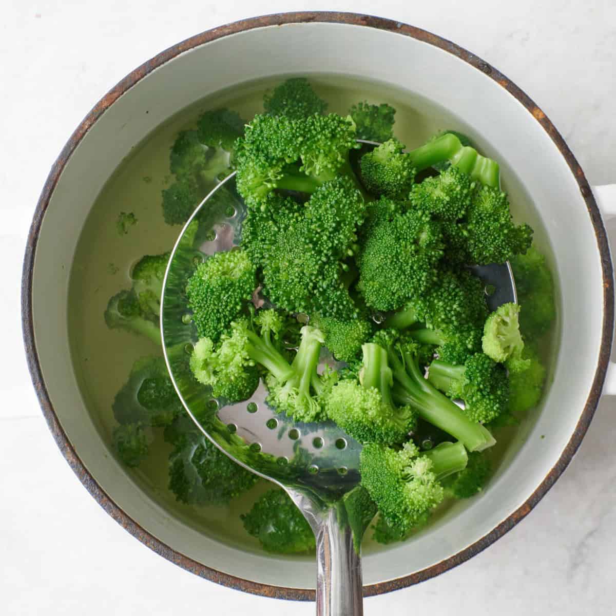 Slotted spoon lifting florets out of the water.