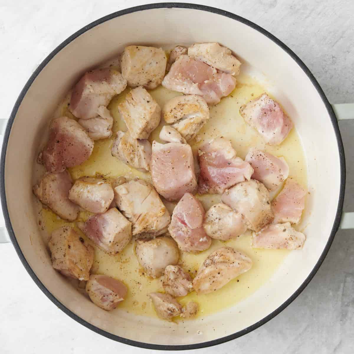 Chicken in a large heavy bottom pot seasoned with salt and pepper, partially cooked.