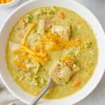 Creamy chicken broccoli soup in a bowl with a spoon, lifting up a bite.