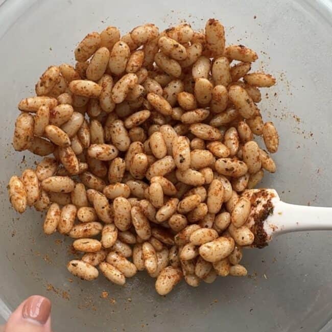 Cooked white beans getting tossed in seasoning before air fried