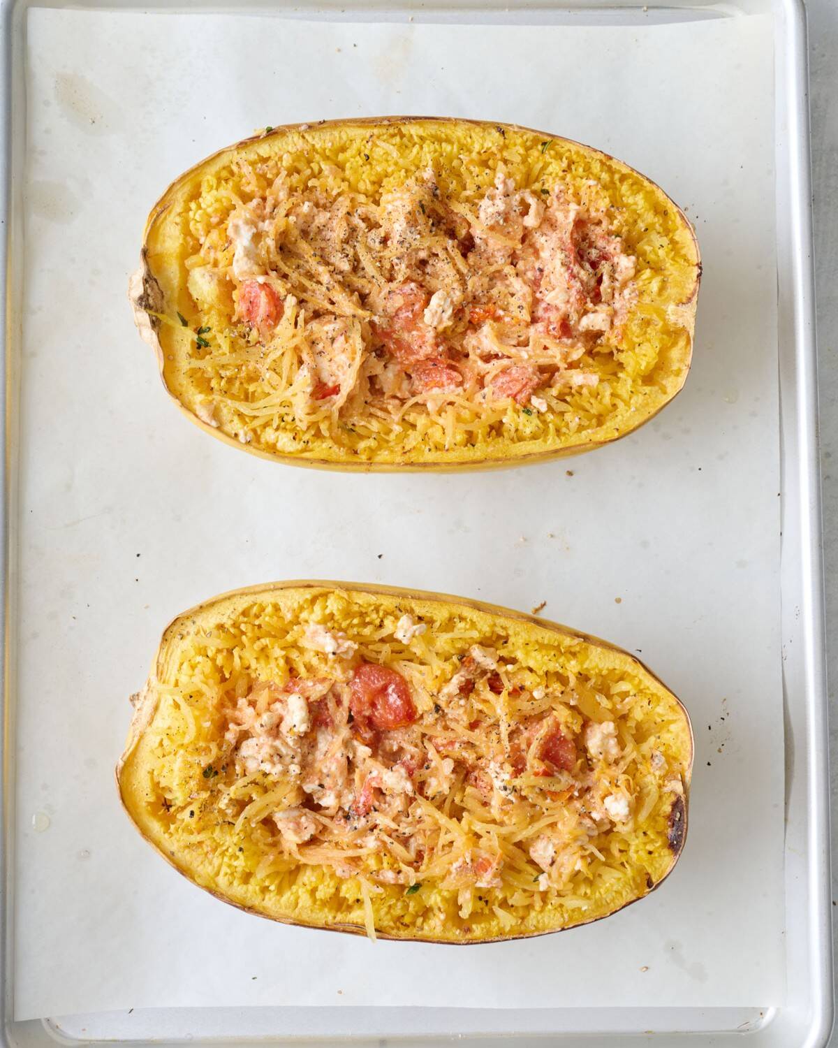 Two feta spaghetti squashes after baking and mixing the contents together to make a boat of feta spaghetti squash.