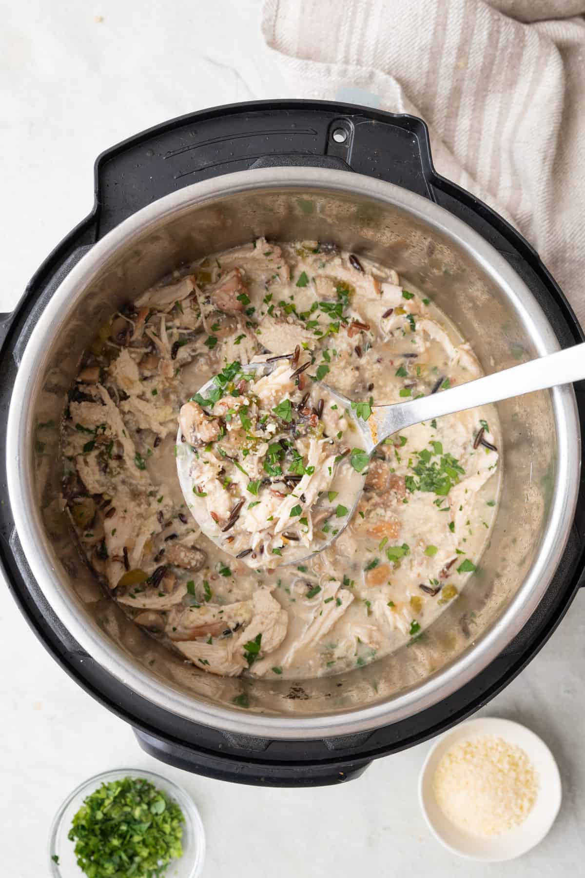 Ladle lifting up chicken and rice from an Instant Pot bowl.