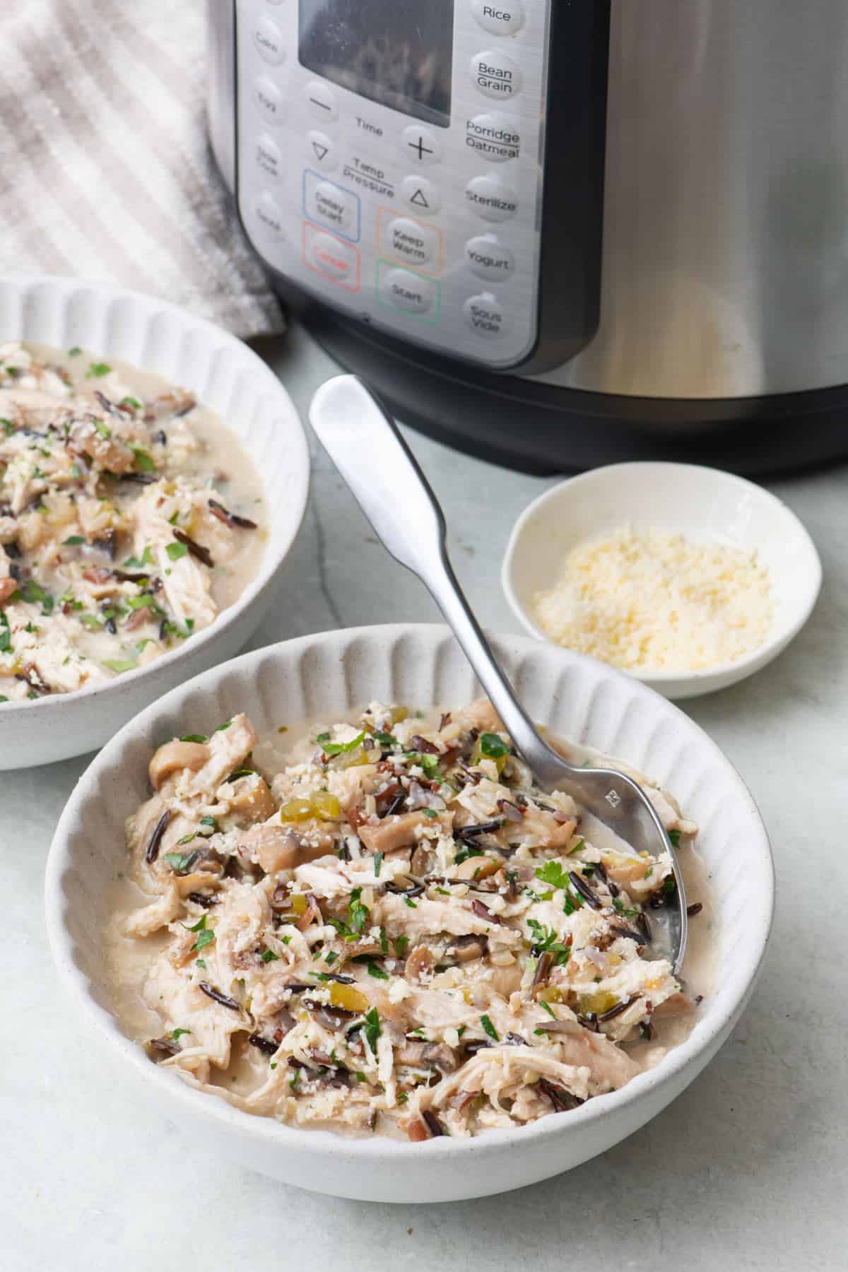 Chicken and rice divided into two bowls with Instant Pot machine nearby.