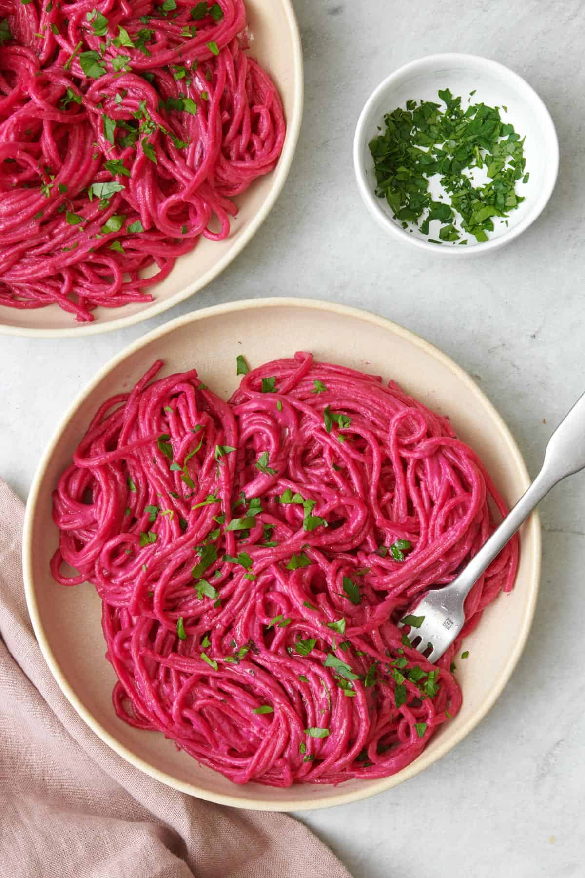 Serving of pink pasta made with roasted beets on a small plate.