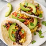 Closeup of 3 breakfast tacos on a white plate.