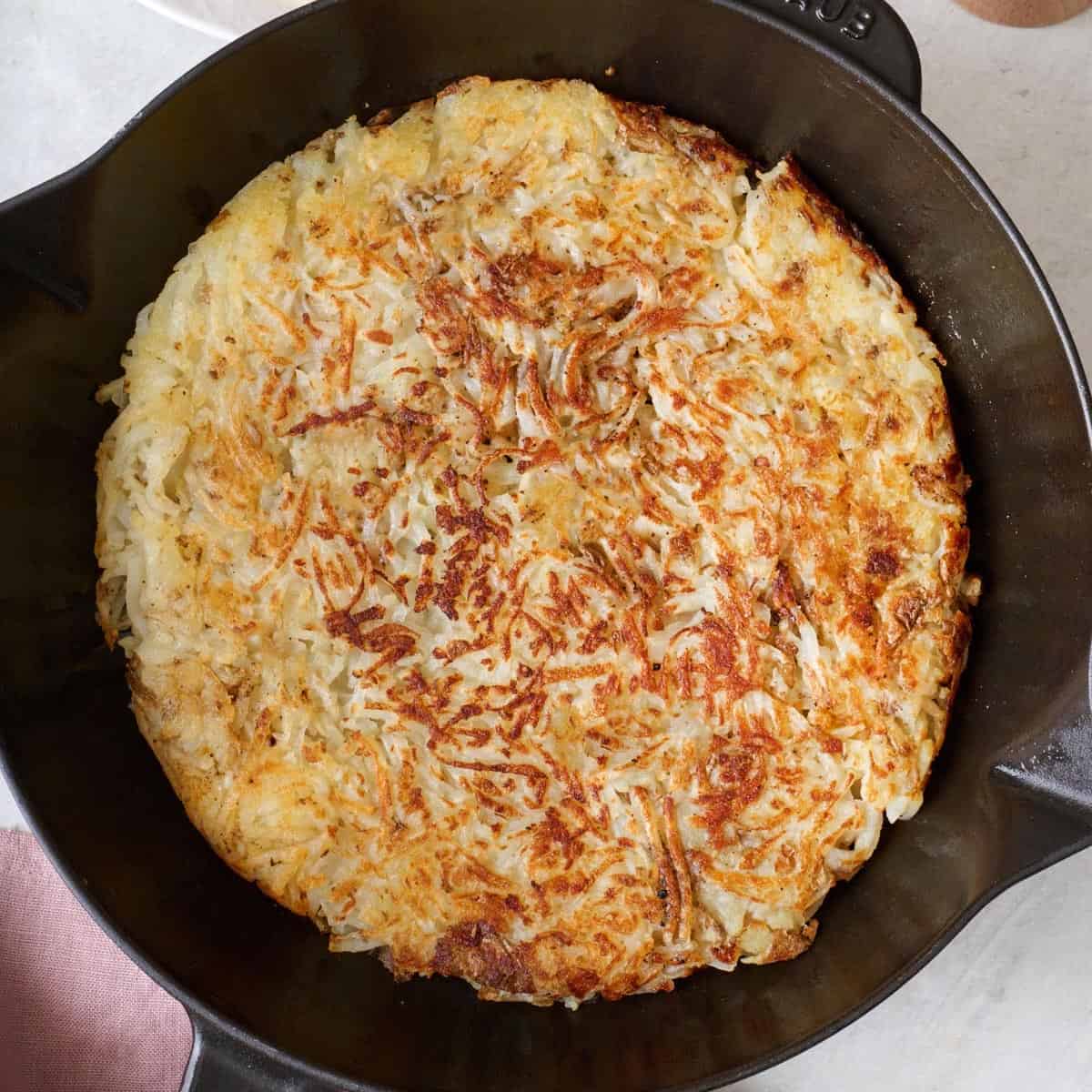 Closeup of crispy hash browns in a cast iron skillet.