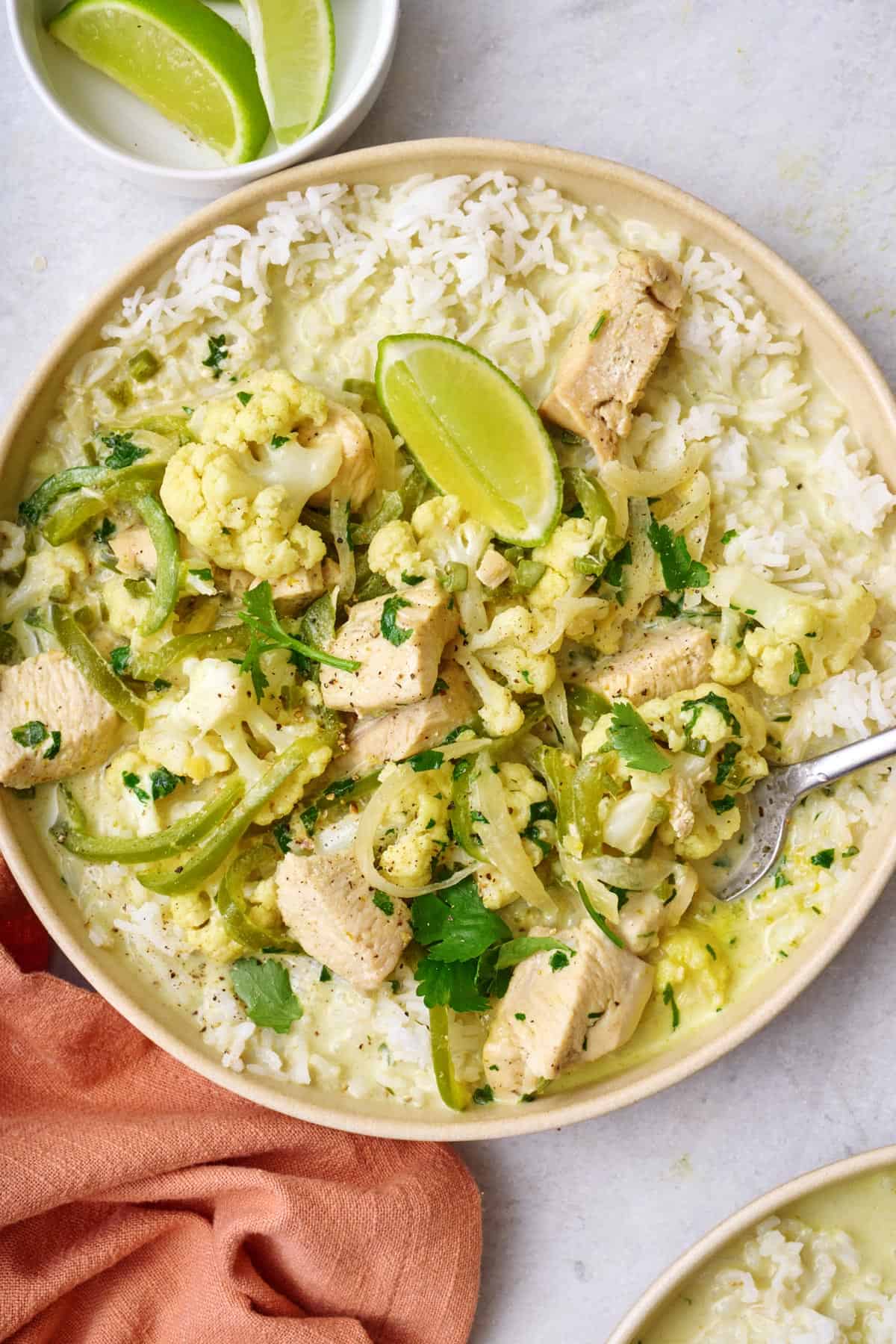 Green Thai curry with chicken served over rice in a bowl with a spoon dipper in.