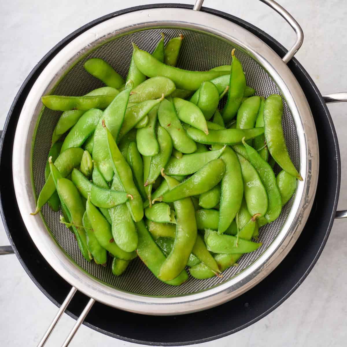 Cooked edamame in a strainer.