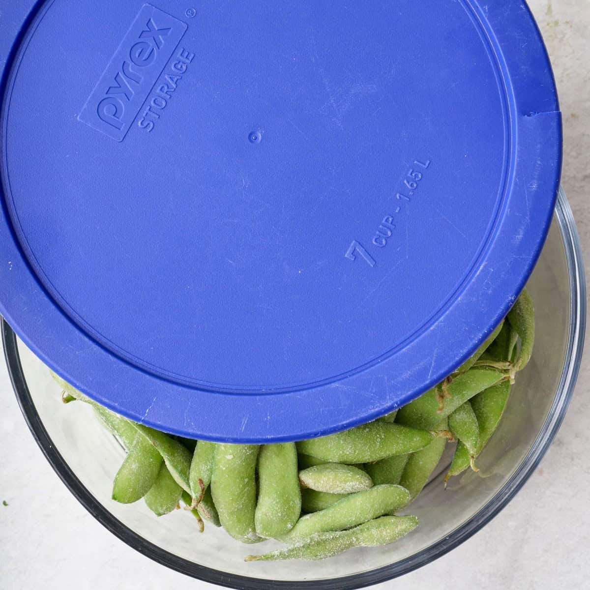 Edamame in a microwave safe bowl with a lid.