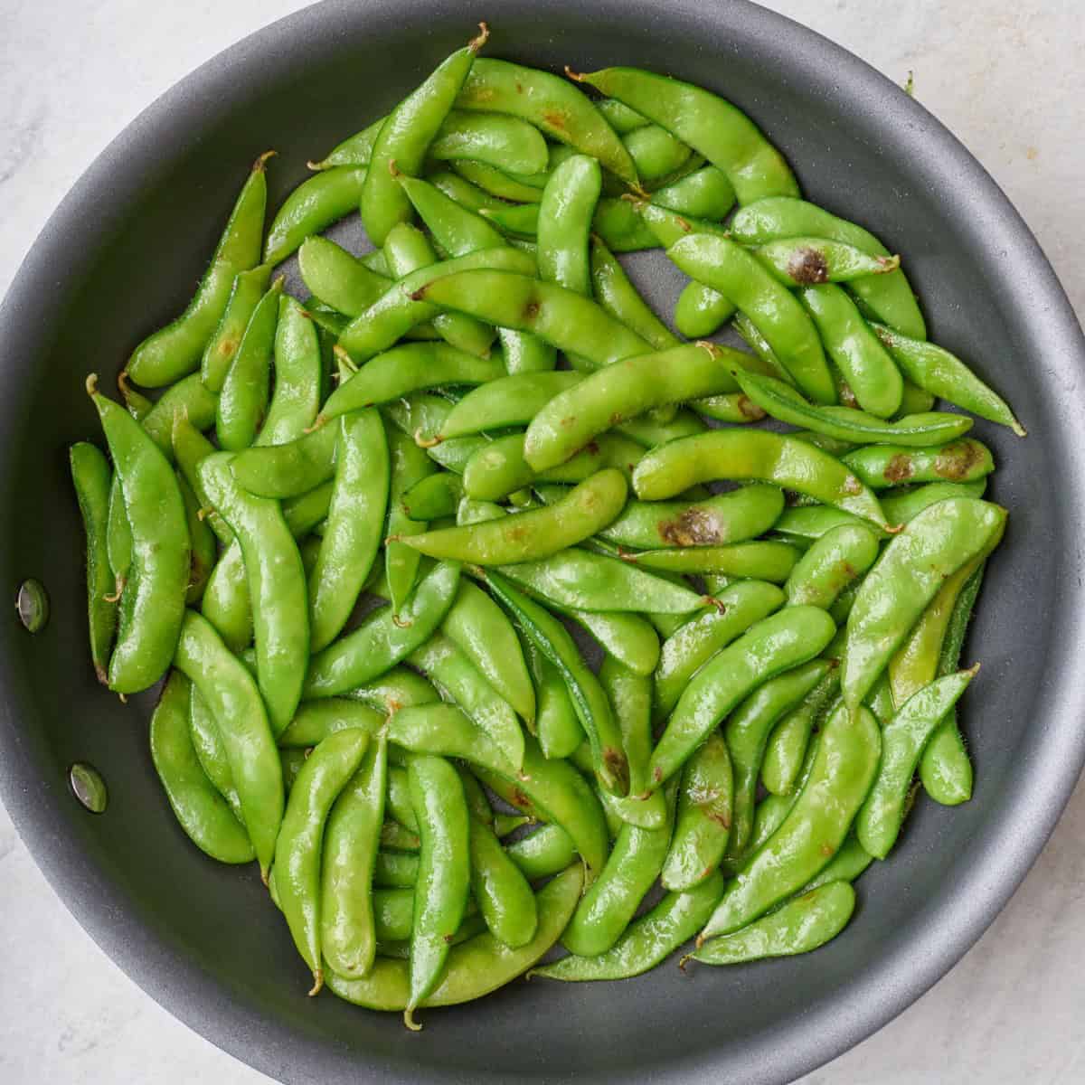 Sauteed edamame in a skillet.