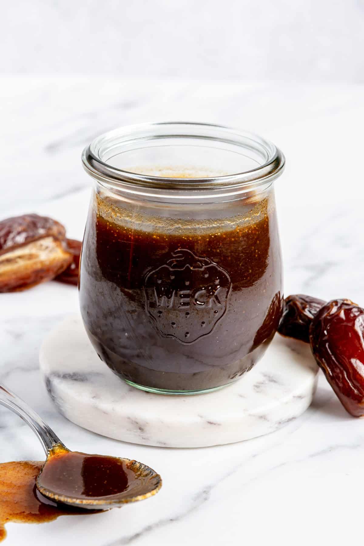 Date syrup in a small jar with more whole dates nearby.