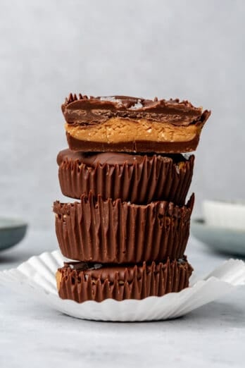 Peanut butter cups with flaky salt stacked on top of each other in a paper liner, the top one cut in half.
