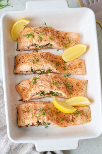 Stuffed salmon fillets in a baking dish with fresh lemon slices.