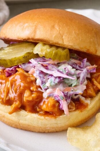 BBQ chicken sandwich on a plate with chips.