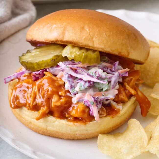 BBQ chicken sandwich on a plate with chips.