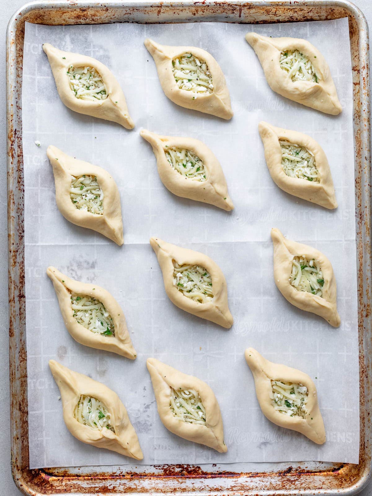 Shaped cheese fatayer on baking sheet before baking.