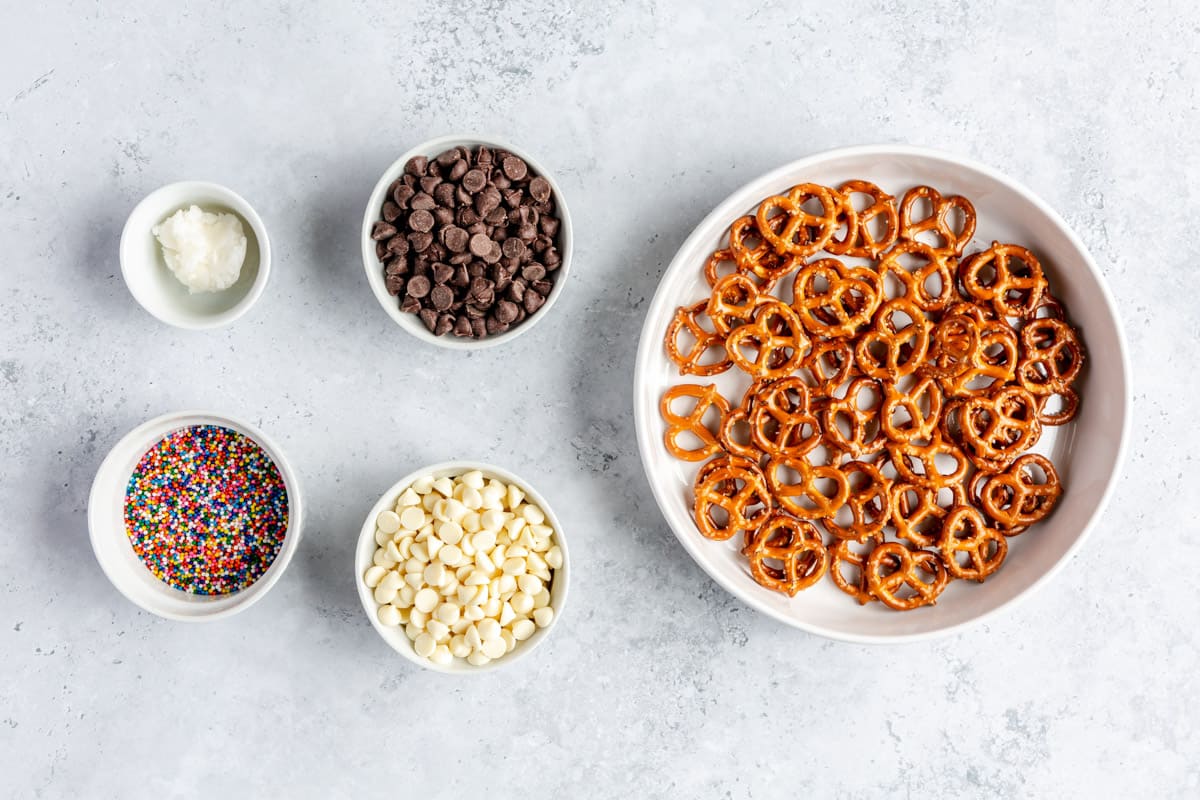 Ingredients for recipe: Pretzels, semi-sweet chocolate chips, white chocolate chips, coconut oil, and rainbow sprinkles.