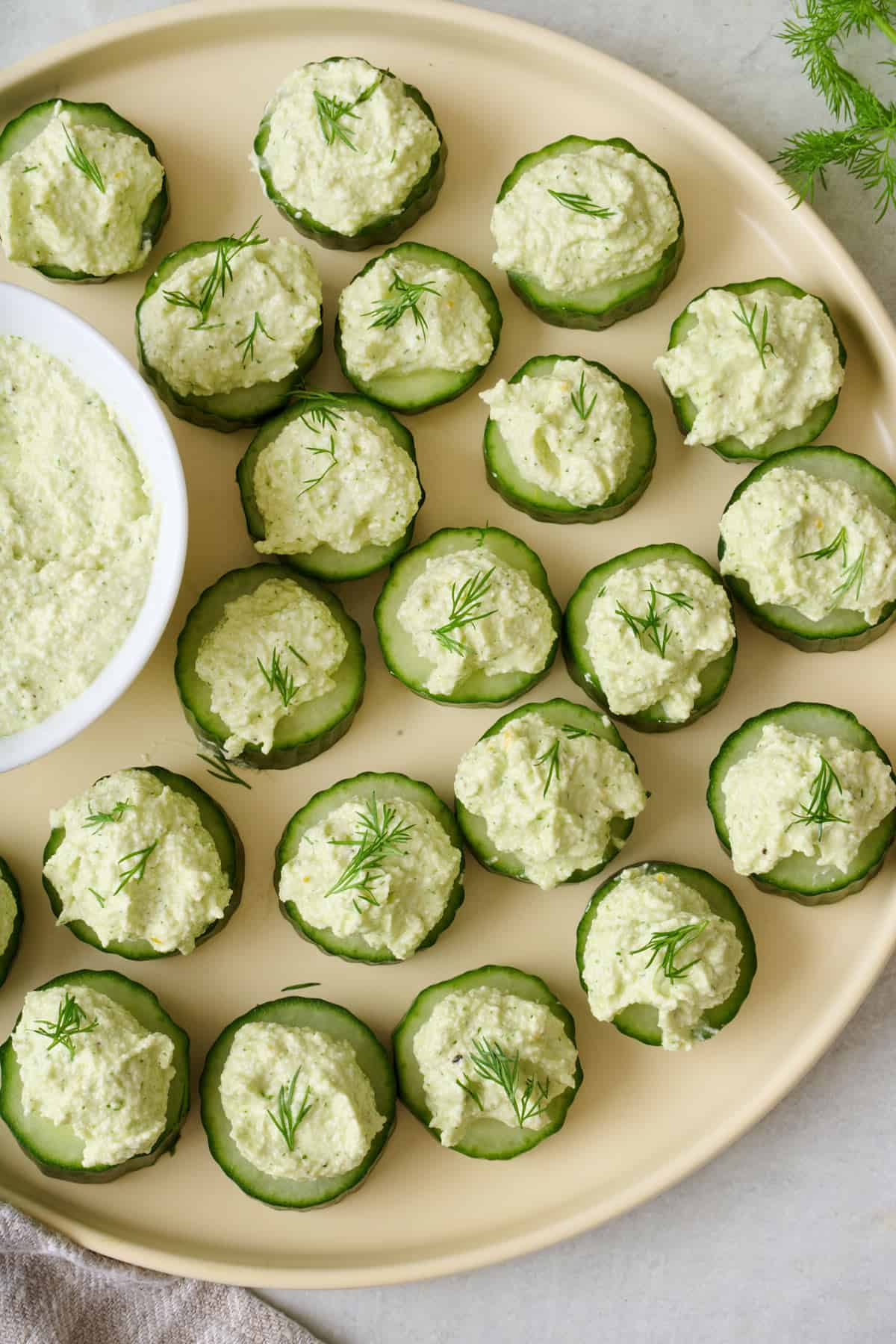 Tray of cucumber canapes with small bowl of whipped feta dip.
