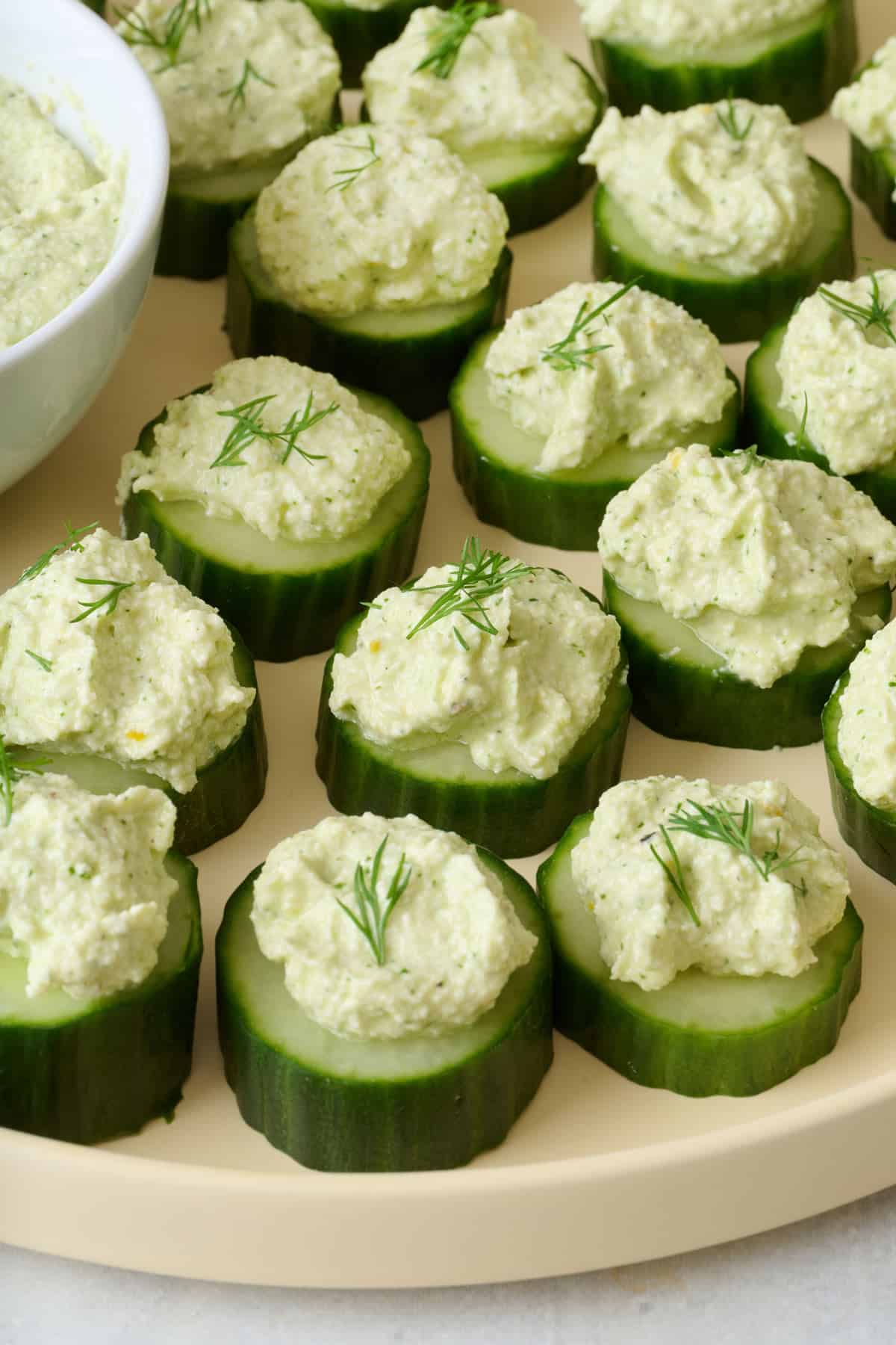 Closeup of cucumber canapes topped with whipped feta and fresh dill.