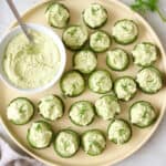 Tray of cucumber canapes with bowl of whipped feta topping.