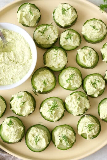 Tray of cucumber canapes with bowl of whipped feta topping.